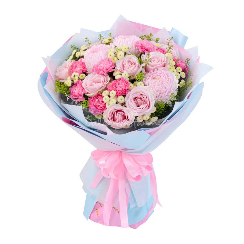 Một bó hoa đa sắc màu rực rỡ, bao gồm hồng, cẩm chướng, ly và lá phụ kiện, được gói cẩn thận, thể hiện một món quà tặng sinh nhật mẹ ý nghĩa và đẹp mắt.